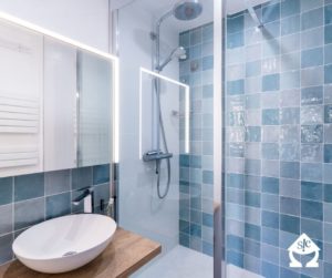 Salle de bain aux tons bleu avec un lavabo sur une surface bois.