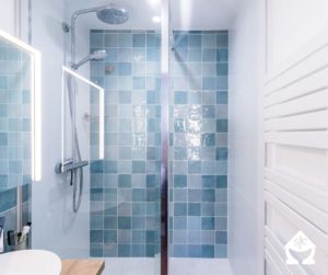 Douche avec des carreaux de différentes teintes de bleu.