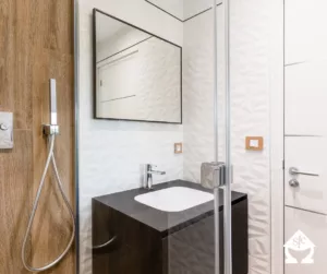Salle de bain blanche avec un miroir aux contours noirs.